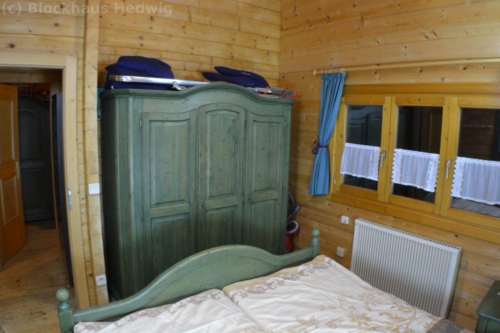 3- türiger Kleiderschrank, Wäschespinne und Staubsauger im Schlafzimmer.