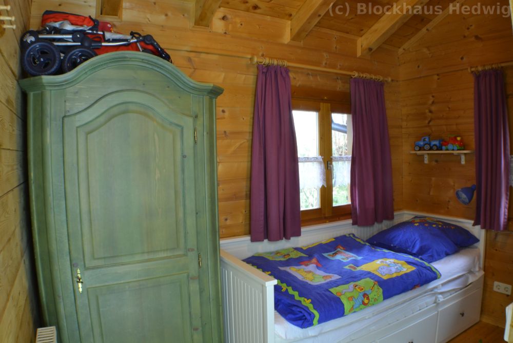 Blick von der Tür ins Schlafzimmer mit ausziehbarem Doppelbett und Schrank