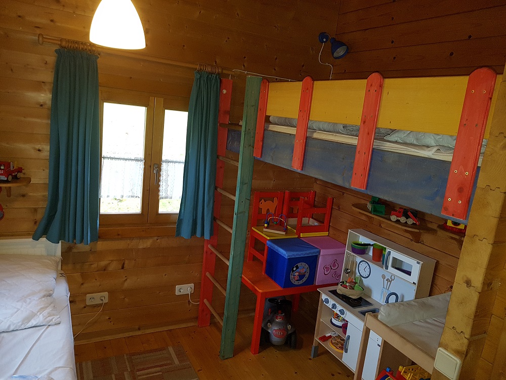 Blick in das 2. Schlafzimmer das auch als Kinderzimmer dient. Ausziehbares Doppelbett, Spielecke, Wickeltisch, Kindersitzecke, Spielzeug und Hochbett über der Spielecke.